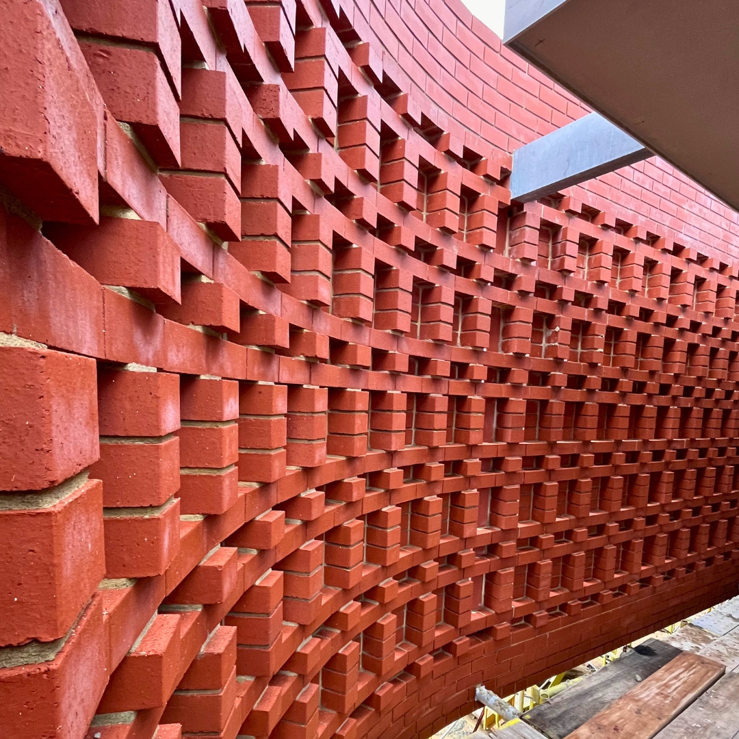 Intricate curved hit-and-miss brickwork feature wall constructed by Red Rock Brickworks in collaboration with Louis Homes
